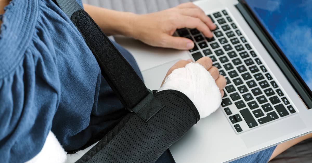 Person with arm in a cast working on a laptop