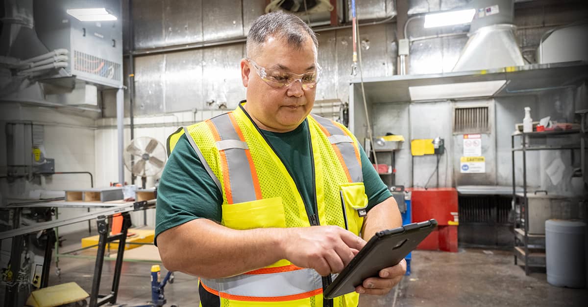 Worker conducting a safety inspection using a tablet in a manufacturing facility