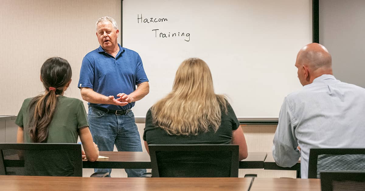 Instructor leading HazCom training session for employees in a classroom.