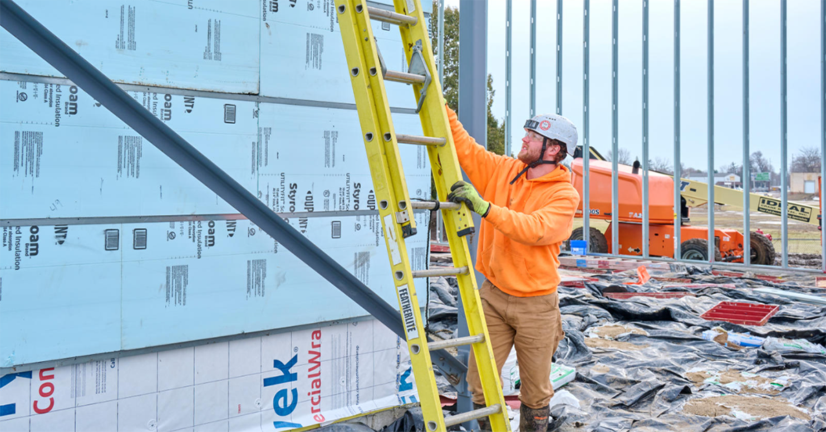man setting up a ladder on a construction site
