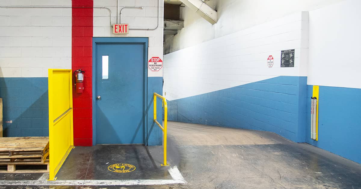 Warehouse exit door with safety railings and exit sign, highlighting OSHA compliance.