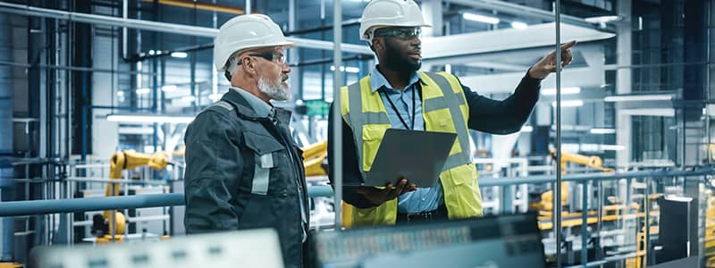 Safety managers conducting a workplace audit in a manufacturing facility using inspection checklists and digital tools to assess compliance.