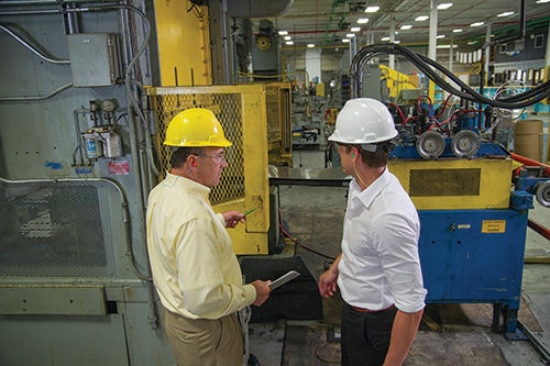 Two males and one female with hardhats holding a laptop