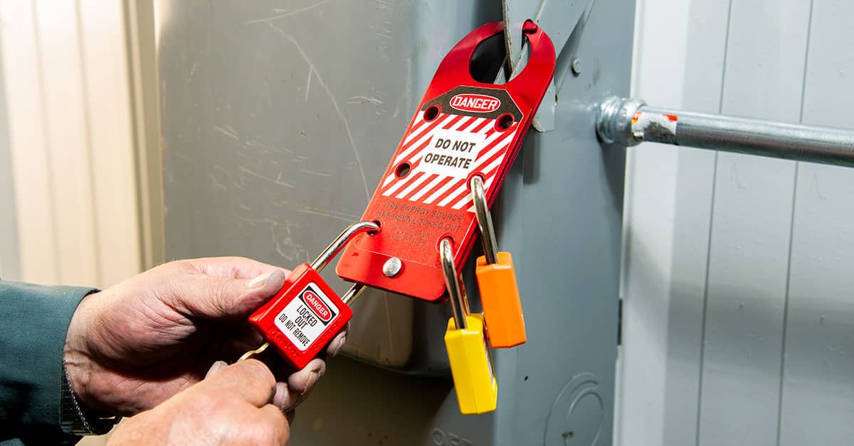 Lockout tagout procedure with multiple padlocks on electrical panel for OSHA safety compliance during equipment maintenance.