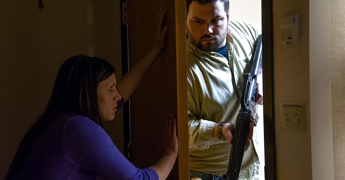 Simulated active shooter entering room with person attempting to block door, illustrating workplace drill scenarios and emergency response training.