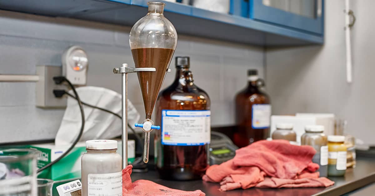 Lab bench with separatory funnel and chemical bottles.