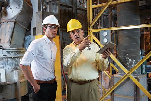 Male safety consultant speaking with another male and pointing to something out of frame