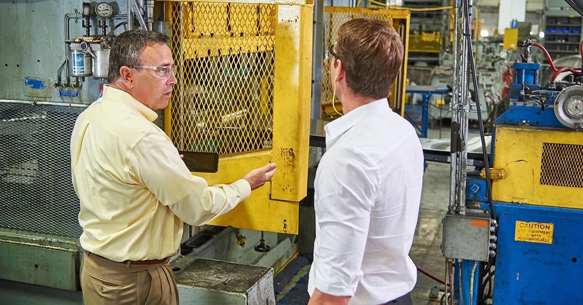 two workers looking at machine guarding in manufacturing plant