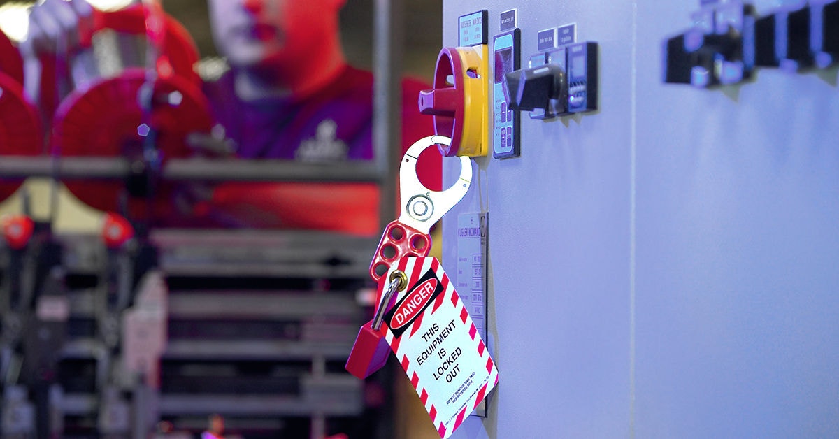 Lockout tagout safety procedure in industrial setting with danger tag and padlock securing electrical switch, ensuring equipment is locked out for maintenance.