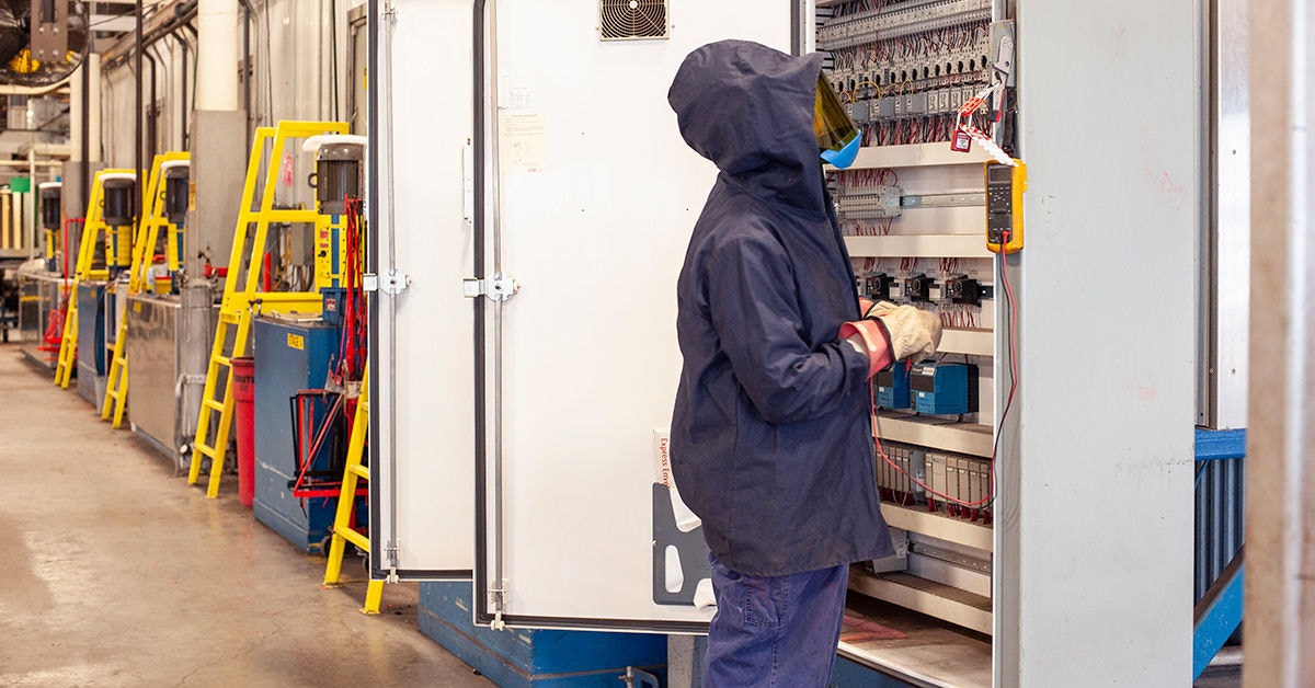 Man with PPE working with large electrical panel