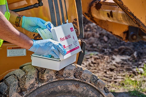 Person carrying an AED toward an injured worker in the distance