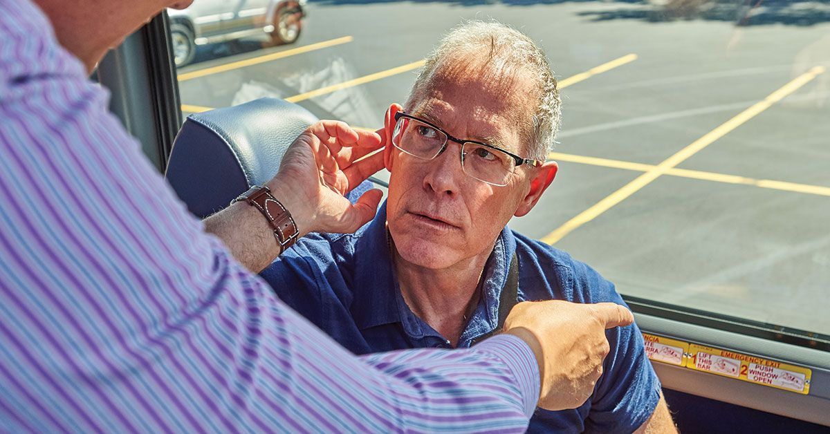 Bus driver assisting elderly passenger, highlighting workplace noise exposure risks and the need for hearing conservation in transportation jobs.