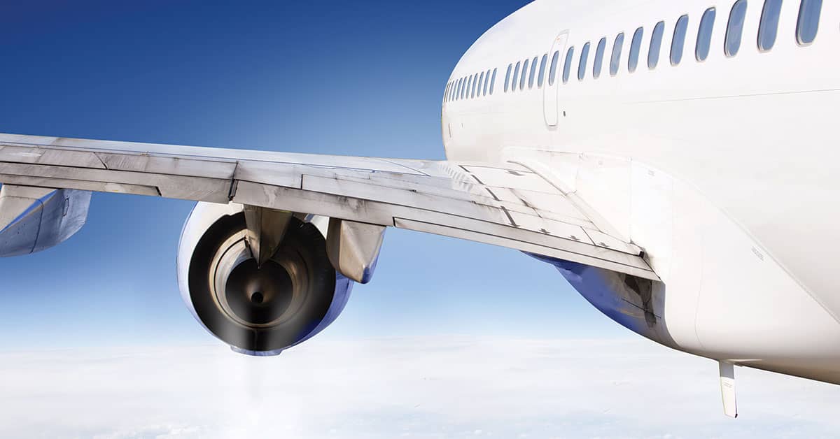 Airplane wing in flight symbolizing business travel and OSHA's rules on work-related injuries during employee trips.