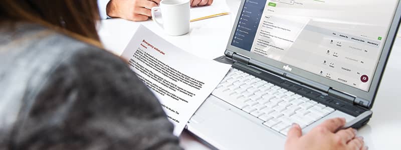 Safety professional reviewing Emergency Response safety plan template from J. J. Keller SAFFETY MANAGEMENT SUITE, the plans & policies section of the site shows on a laptop screen.