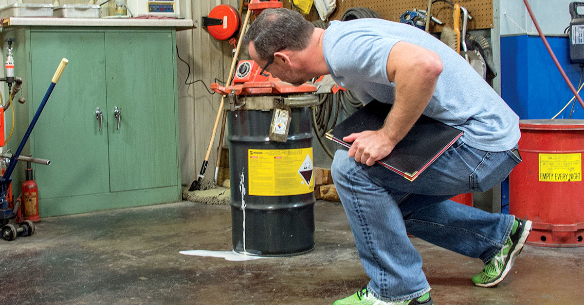 Worker inspecting chemical spill in industrial workshop, emphasizing safety protocols and hazard management.