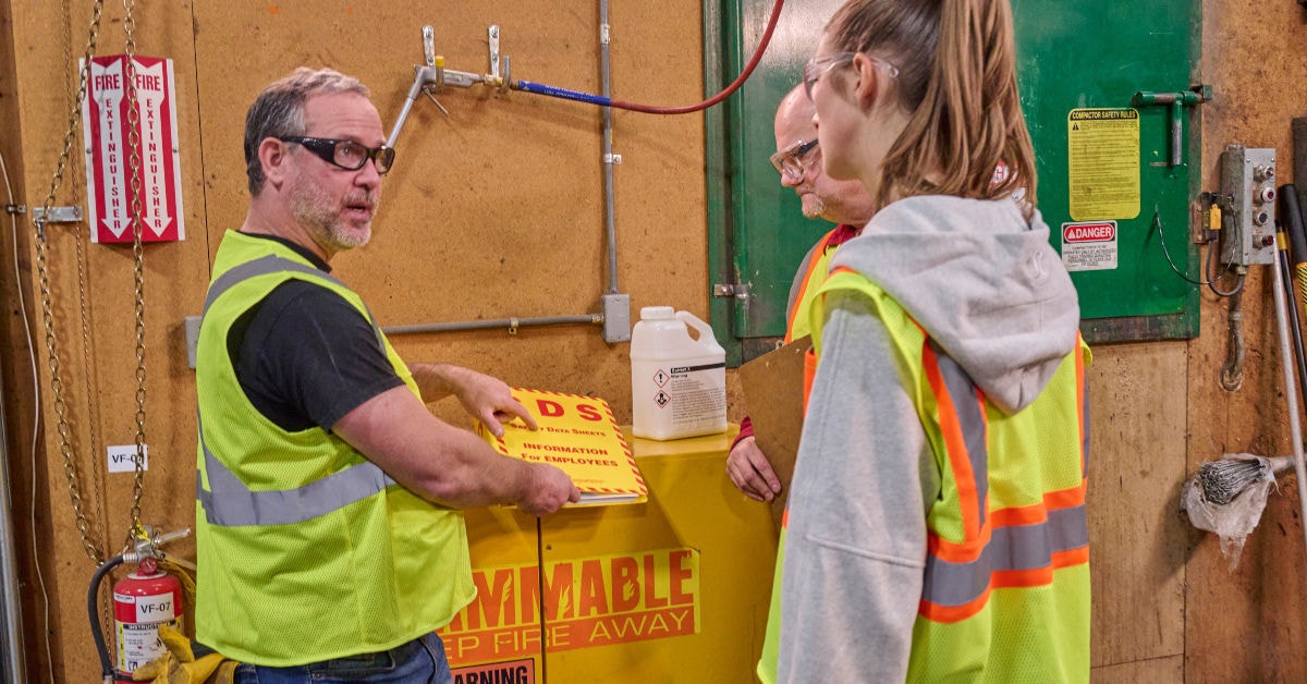 Three people in the workplace discussing safety data sheets