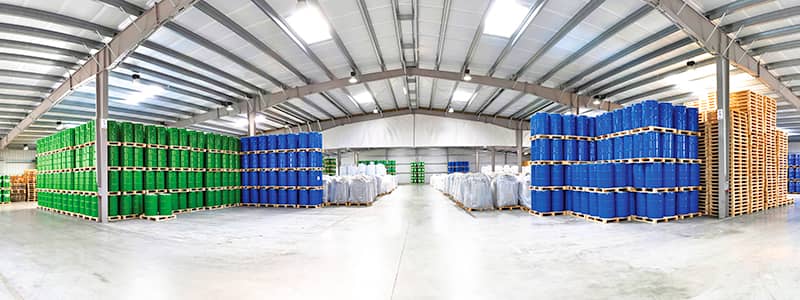 Organized warehouse with chemical containers on pallets, illustrating safe storage practices supported by chemical management software and SDS access.