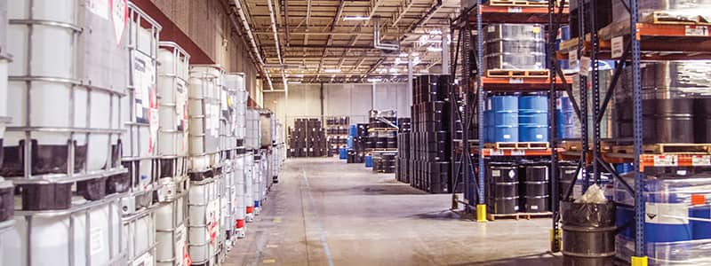 Industrial warehouse with chemical storage drums, illustrating the need for chemical management solutions including SDS documentation and GHS-compliant labeling.