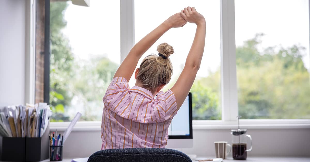 Back view of woman stretching at her desk