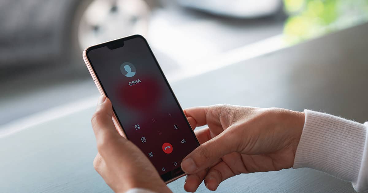 Hand holding a cell phone with OSHA queued up on the screen