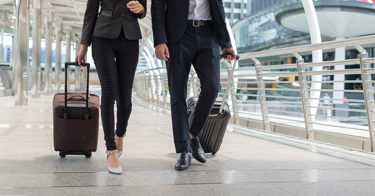 business man and business woman walk together luggage on the public street, business travel