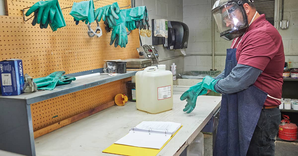 Worker with PPE referencing a safety data sheet prior to handling a chemical