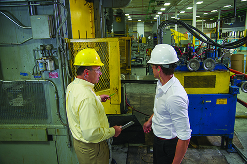 Two males and one female with hardhats holding a laptop