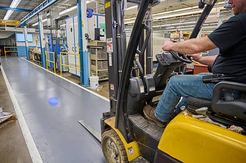 Forklift being driven down an aisle in industrial setting