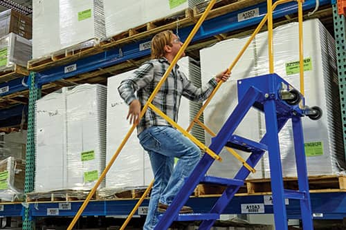 Male worker climbing a portable ladder in a warehouse